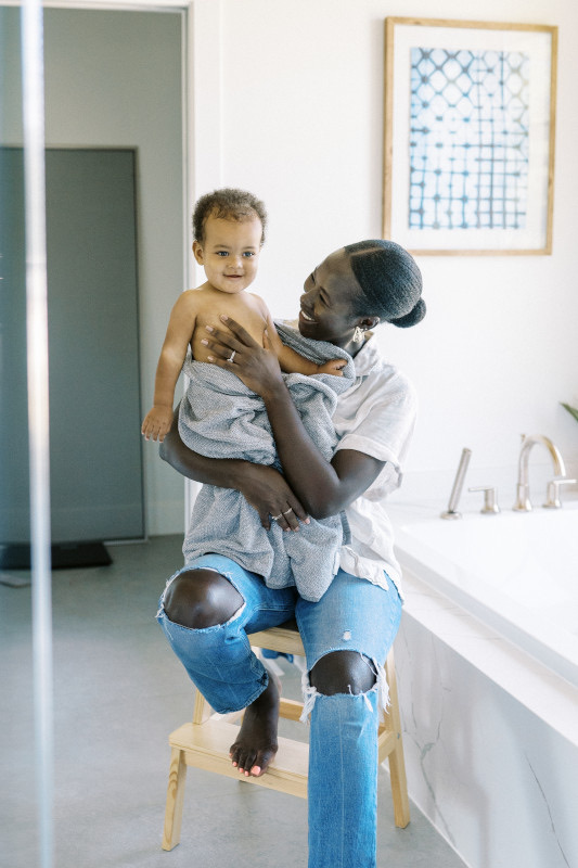 Bebé disfrutando de su baño diario en bañera especial mientras el cuidador lo sostiene con seguridad