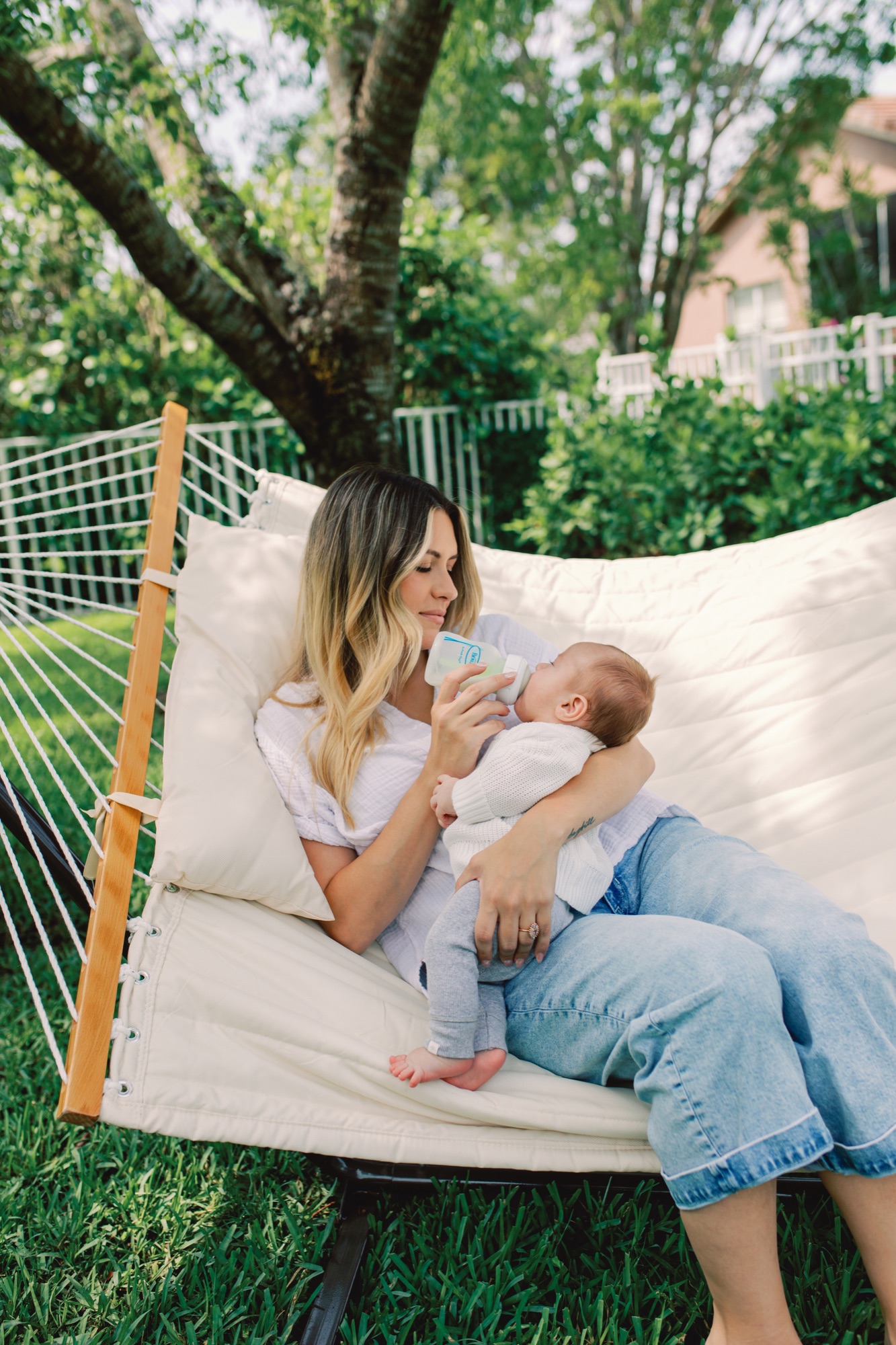 Mamá dando mamadera Dr. Brown's al bebé en hamaca al aire libre durante un paseo