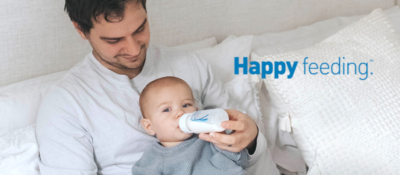 Papá dando mamadera con leche materna almacenada a su bebé, usando el stock del banco de leche