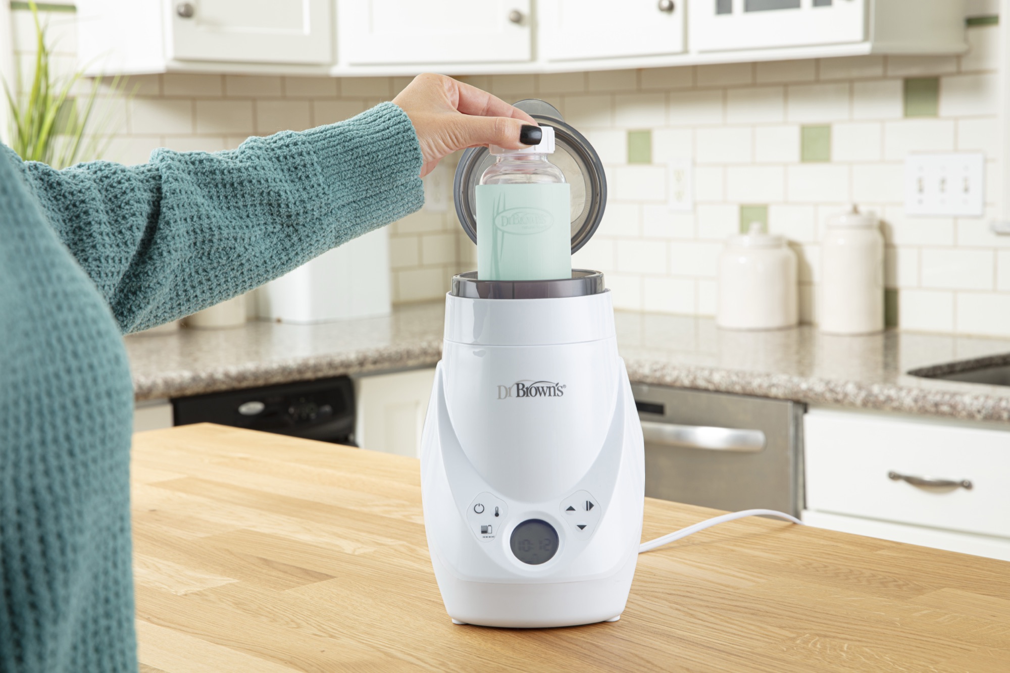 Mamá usando el calentador y esterilizador de mamaderas Dr. Brown's Deluxe en la cocina