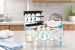 Set Recién Nacido Completo Dr. Brown's —mamaderas boca ancha, esterilizador para microondas, rack de secado, jarra y cepillo— sobre el mesón de una cocina luminosa